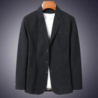 Black cotton blazer on a wooden hanger against a dark background, highlighting the notch lapel