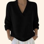Detail shot of a black V-neck jumper showing its ribbed collar, dropped shoulder seams and relaxed silhouette