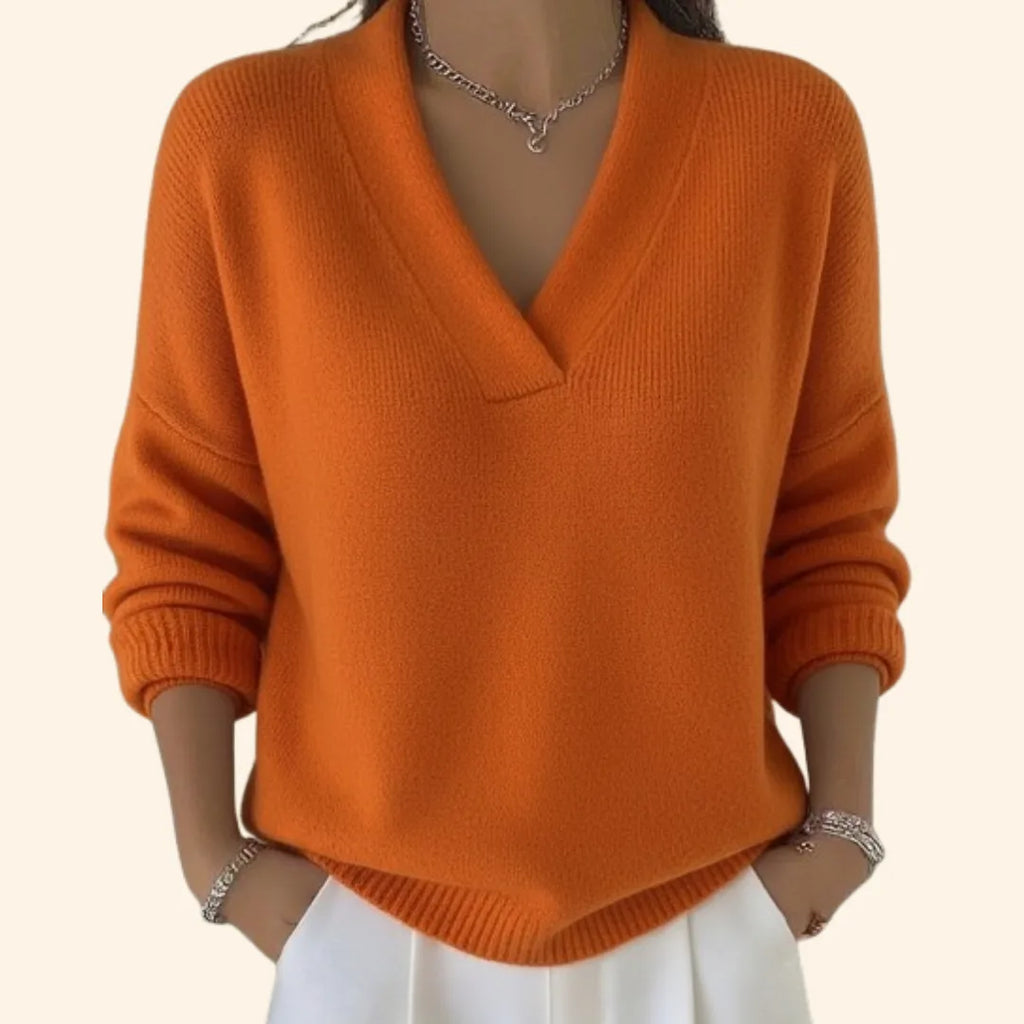 Close-up of a burnt orange V-neck jumper with a soft knit texture, ribbed cuffs and curved hem