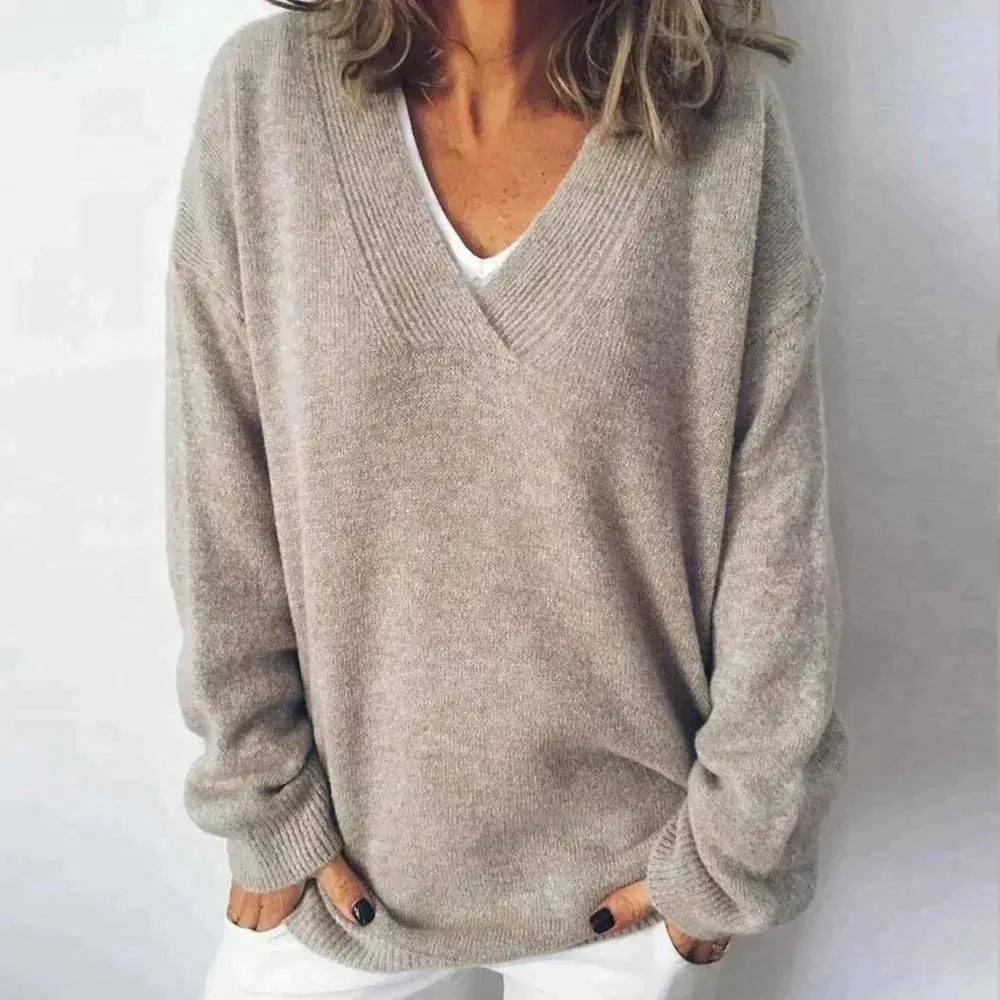 Close-up of taupe oversized V-neck jumper with ribbed knit collar layered over a white top
