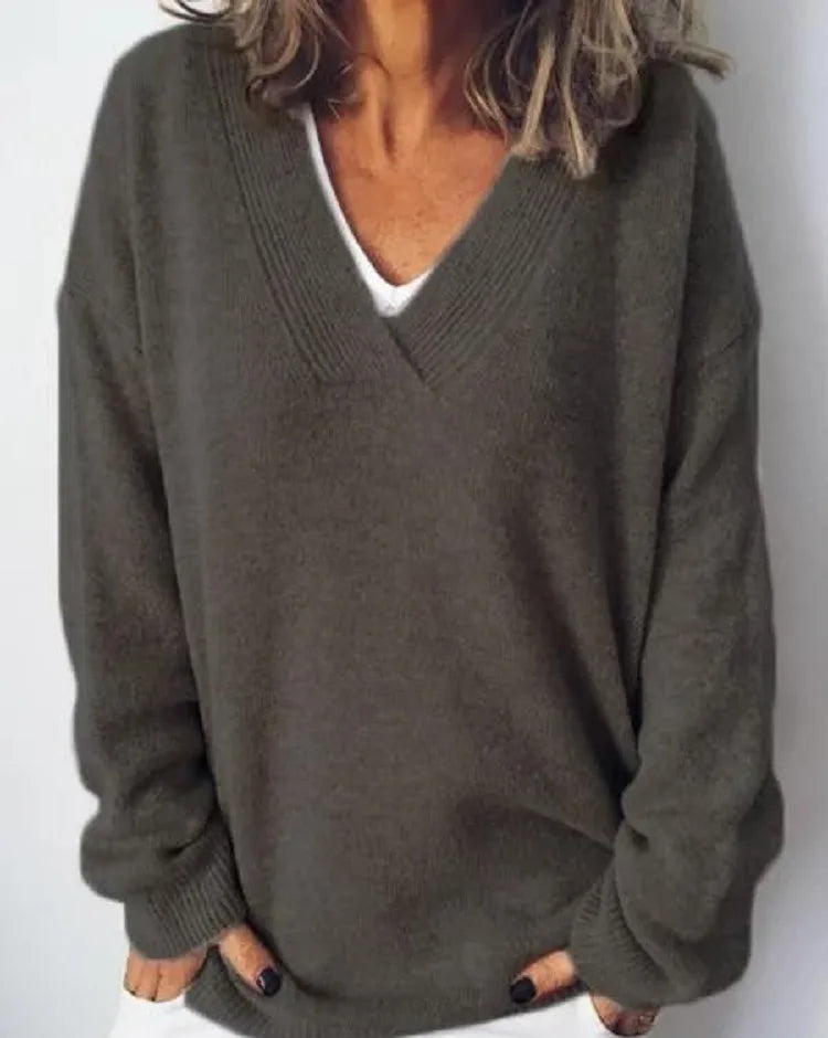 Close-up of an olive green oversized V-neck jumper showing the relaxed knit texture