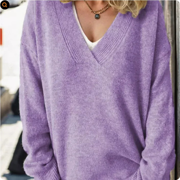 Close-up of a lilac purple V-neck jumper worn with a layered necklace over a white top
