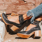 Black snake-print leather ankle strap heels resting on a ledge showing the sole and heel