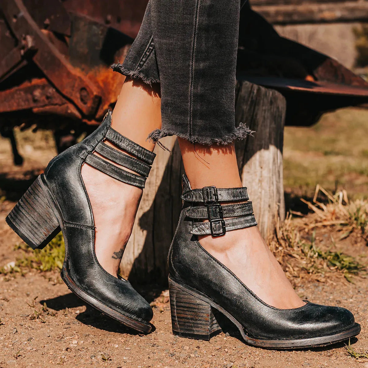 Close-up of black leather ankle strap heels with three buckle straps and rounded toe