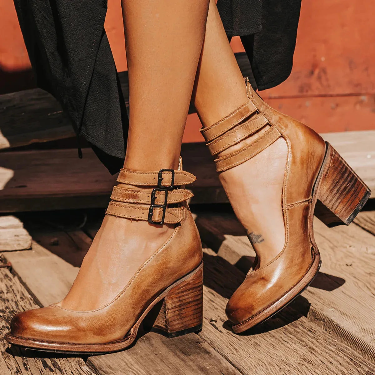 Tan leather ankle strap heels shown from behind highlighting the rear zip and heel stitching