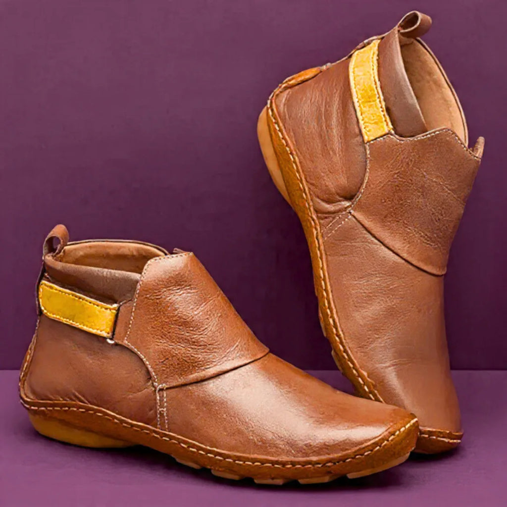 Tan brown leather ankle boots with mustard side strap, shown from front and back angle on purple backdrop