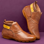 Tan brown leather ankle boots with mustard side strap, shown from front and back angle on purple backdrop