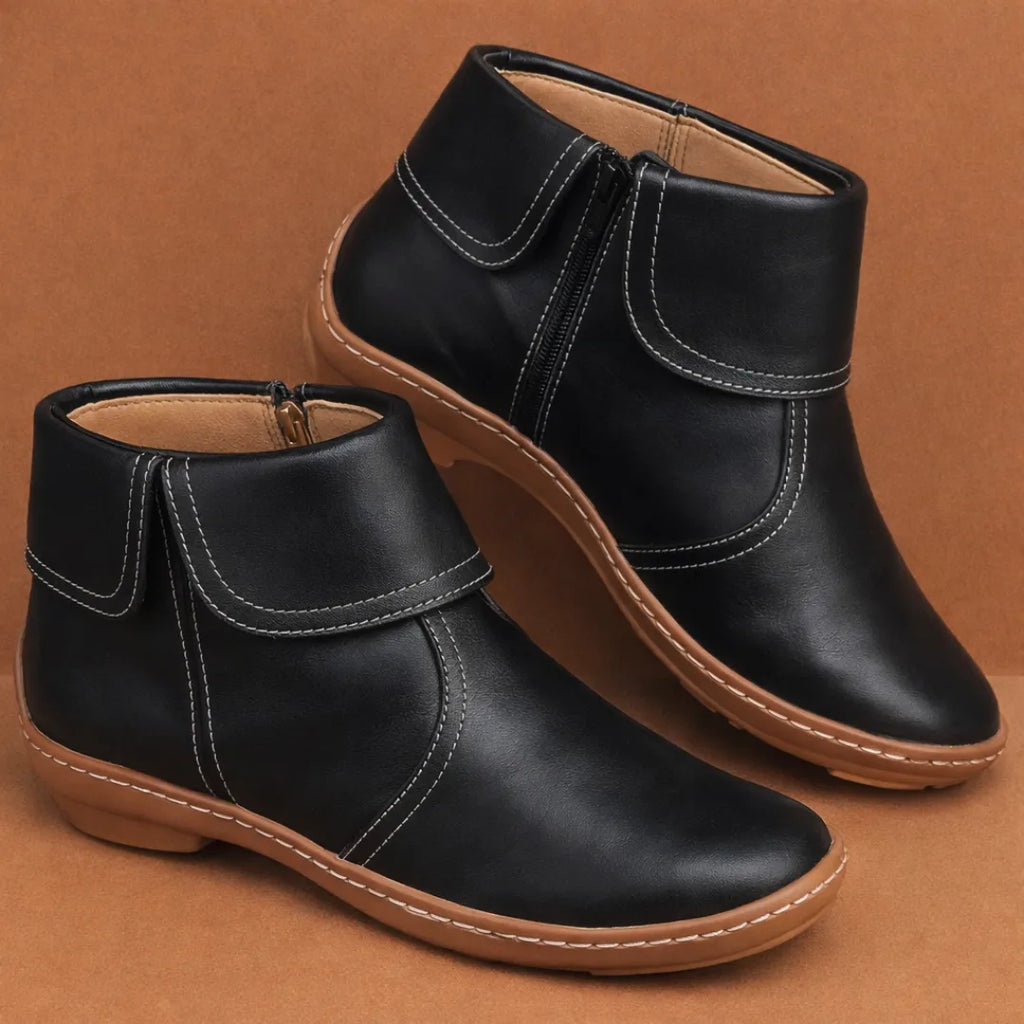Close side view of a leather ankle boot highlighting the flexible ridged outsole and hand stitched seams