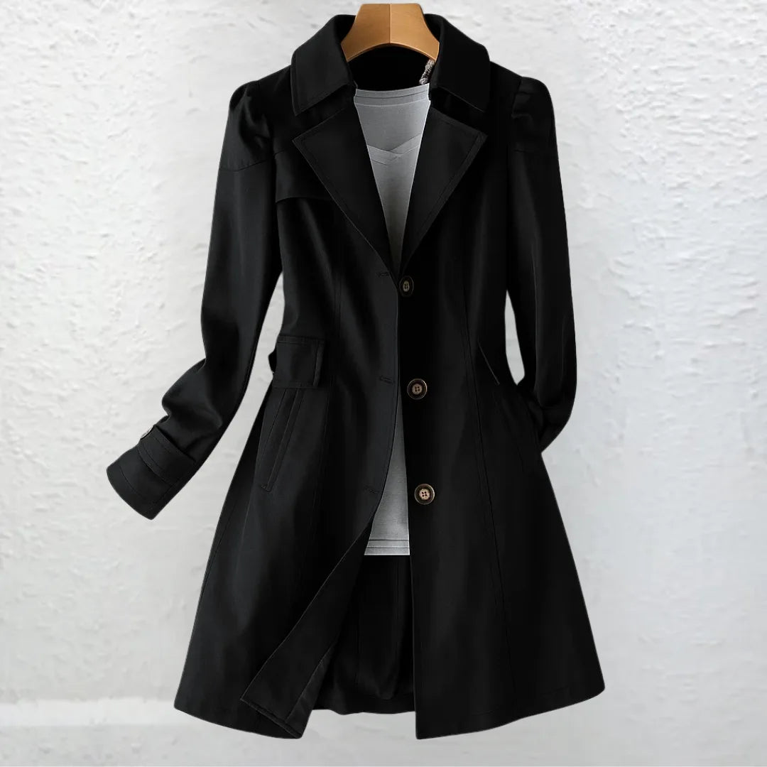 Front view of black tailored trench coat worn open over a grey layered top, showing wide notch collar