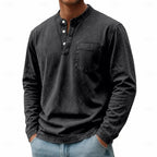Man wearing a black washed henley shirt showing the open collar and three-button placket