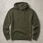 Army green waffle-knit pullover hoodie with cowl neck, drawstrings and ribbed cuffs on a stone backdrop