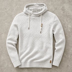 White marl waffle-knit hoodie laid flat, showing cowl collar and chunky knit texture up close