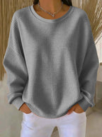 Grey waffle-knit jumper with long dropped sleeves and ribbed cuffs, styled with white trousers