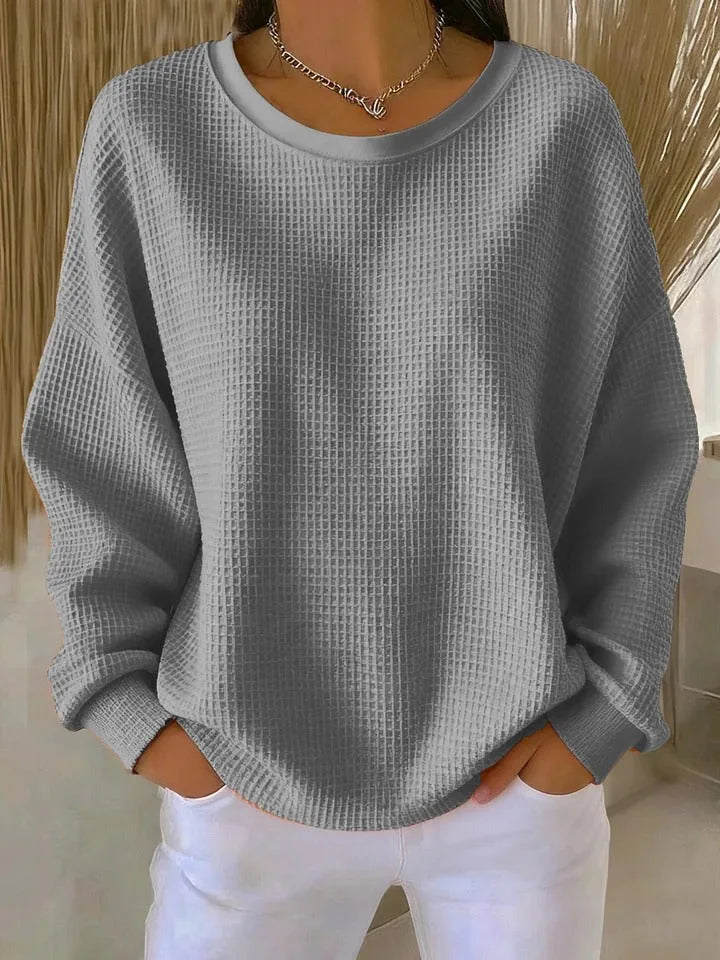 Grey waffle-knit jumper with long dropped sleeves and ribbed cuffs, styled with white trousers