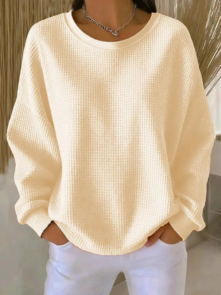 Cream waffle-knit jumper with round neckline, soft textured fabric visible in natural light