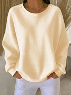 Cream waffle-knit jumper with round neckline, soft textured fabric visible in natural light