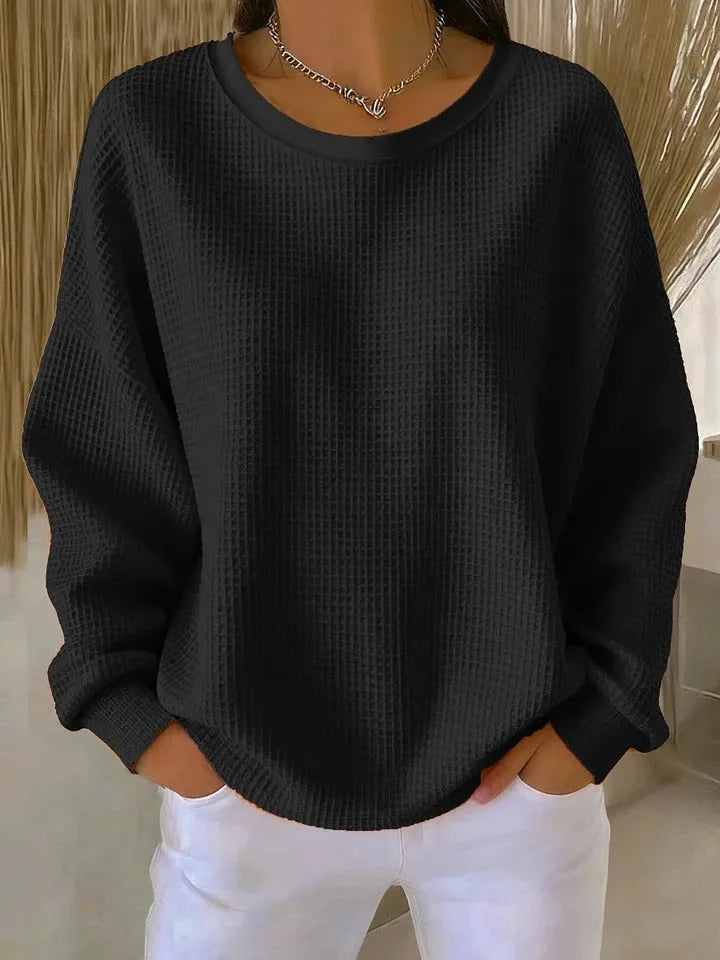 Black waffle-knit jumper with relaxed oversized fit and ribbed cuffs, paired with white trousers