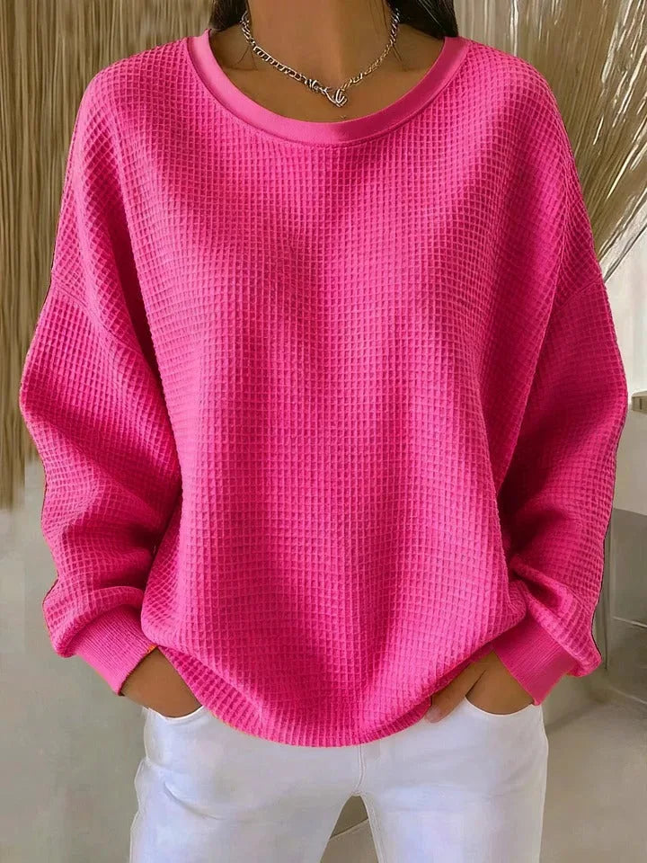 Close detail of waffle-knit texture on a pale blue jumper showing the grid-like fabric pattern