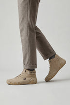 Man walking in beige suede high-top trainer boots paired with grey herringbone tailored trousers