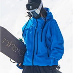 Front view of a vivid blue waterproof ski jacket with full-length zip and toggle drawstrings, worn while holding a snowboard