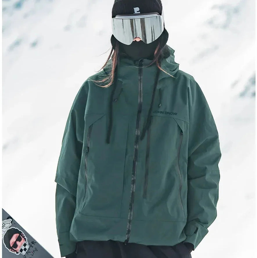 Model wearing a forest green hooded ski jacket with contrast black zips and drawcords against a snowy backdrop
