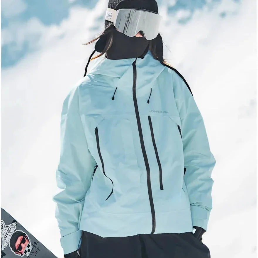 Pale blue hooded ski jacket with visible chest logo and dual zip pockets, worn over black ski trousers