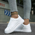 Top-down close-up of white trainer laces and stitched toe cap while worn with jeans