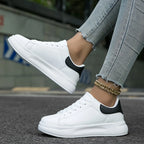 Side angle of white platform trainer with contrast black heel tab, laces loosely tied