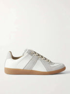 Side profile of a white leather trainer with grey suede panel stripes and a gum rubber sole