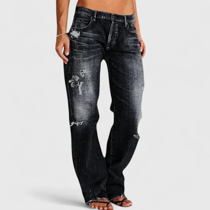Front view of black distressed jeans with faded whiskering and torn detailing on the thigh and knee.