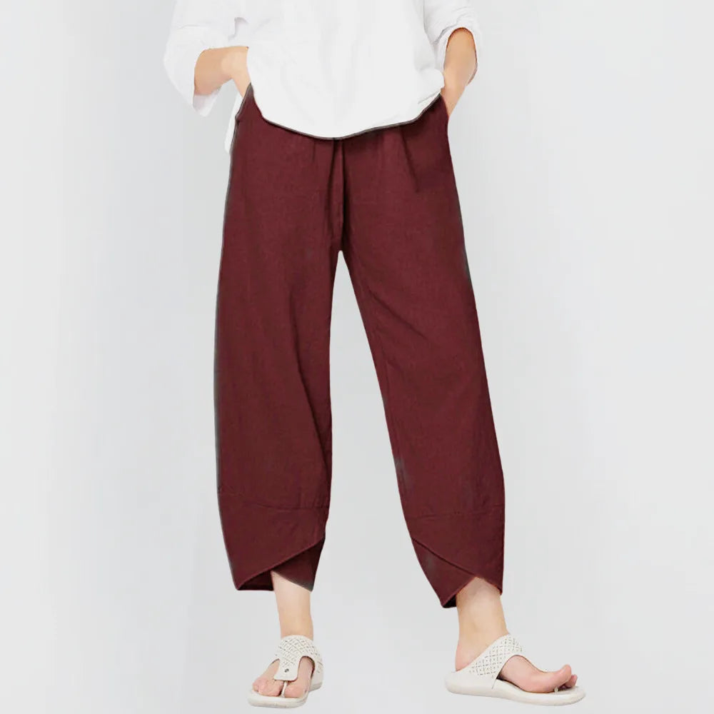 Front view of deep burgundy wide-leg linen-blend trousers with wrap-style curved hem, paired with sandals