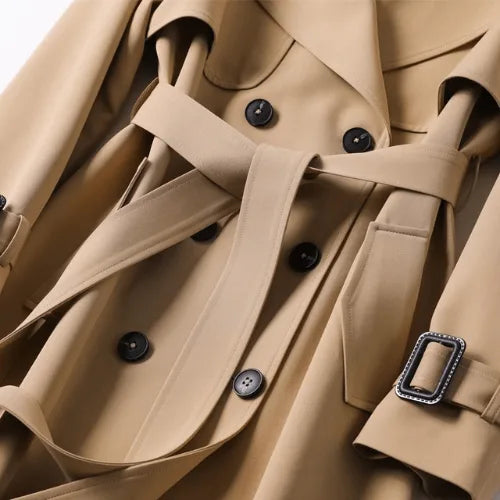 Close-up of the khaki trench coat's waist belt, button placket and buckled tab detail