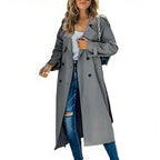 Grey longline trench coat with wide lapels and button-front detail, styled over ripped denim jeans.