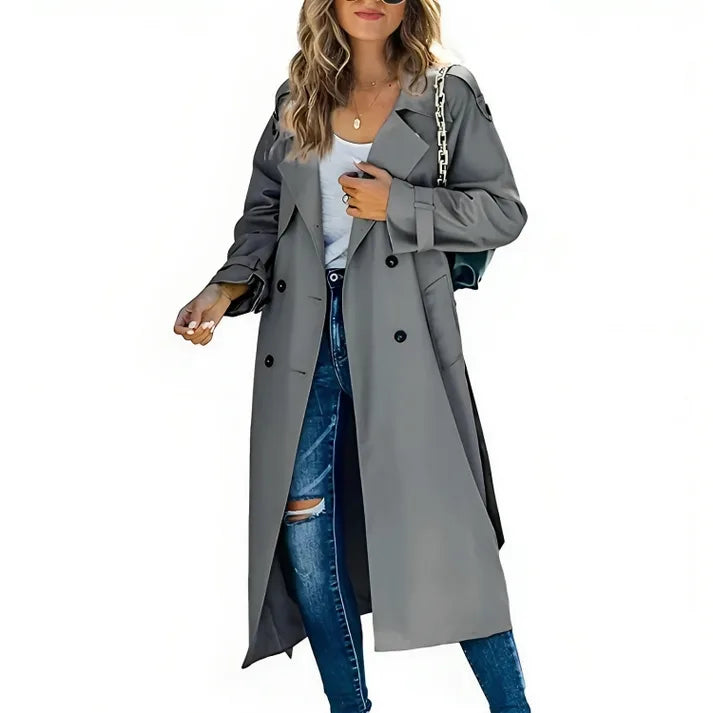 Grey longline trench coat with wide lapels and button-front detail, styled over ripped denim jeans.