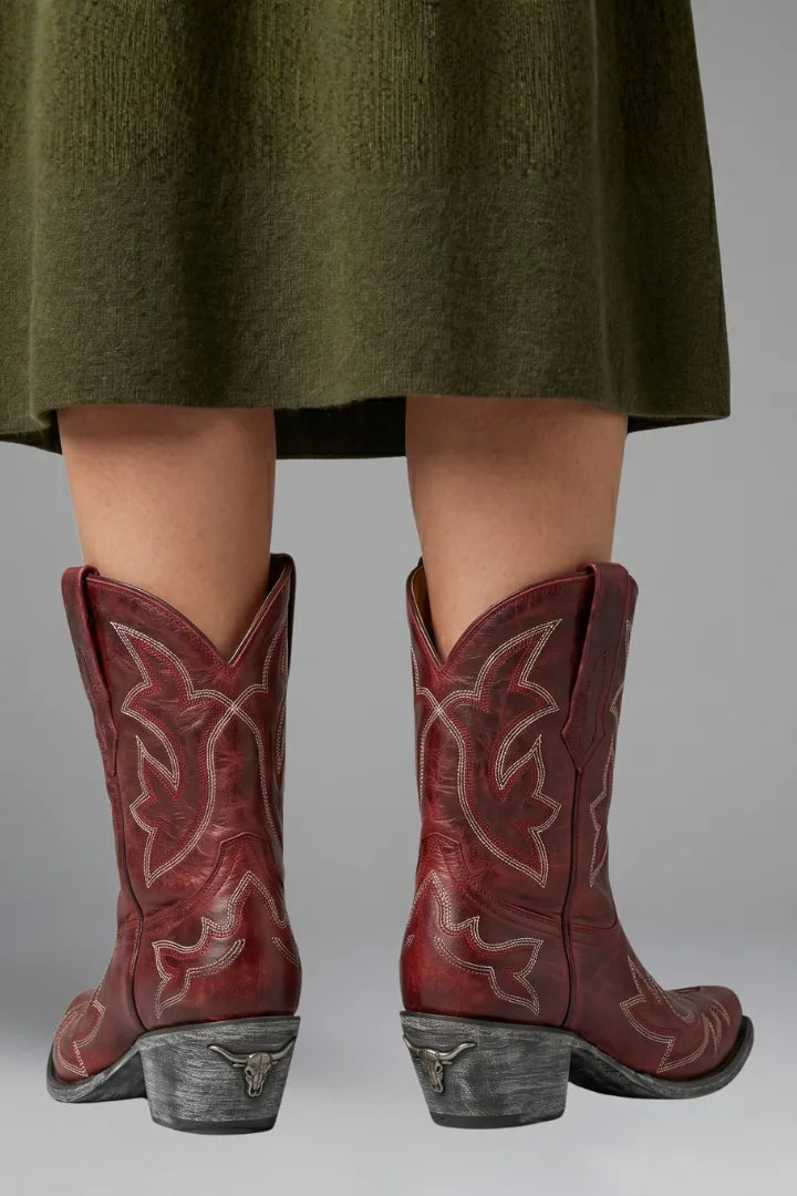 Rear view of red leather cowboy boots showing V-notch topline, cream stitching and longhorn heel emblem
