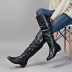 Black over-the-knee slouch boots with ruched leather shaft, worn with jeans and a cream jumper.