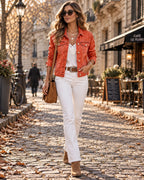 Orange washed denim jacket worn open over white lace cami with white bootcut jeans and tan suede ankle boots