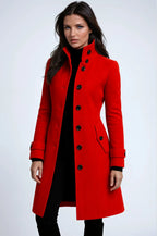 Close-up front view of a red wool coat with high collar, black buttons and belted cuffs worn over a black polo neck