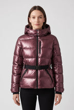 Front view of a woman wearing a metallic burgundy hooded puffer jacket with belted waist and black zip