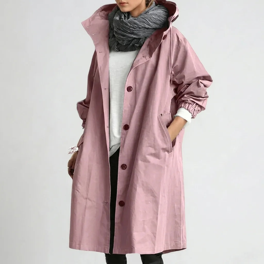 Dusty pink hooded raincoat worn open over a grey knit scarf, showing burgundy button placket and relaxed oversized fit