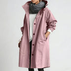 Dusty pink hooded raincoat worn open over a grey knit scarf, showing burgundy button placket and relaxed oversized fit