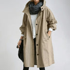 Khaki hooded raincoat with hood drawstring pulled to one side, showing the slash pocket and long below-knee hem