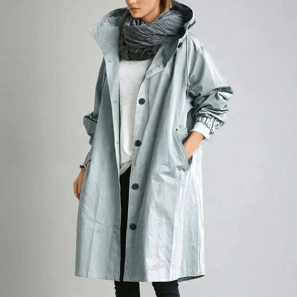 Pale blue-grey hooded raincoat with elasticated cuff detail and standing collar, worn with a chunky grey scarf