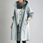 Pale blue-grey hooded raincoat with elasticated cuff detail and standing collar, worn with a chunky grey scarf