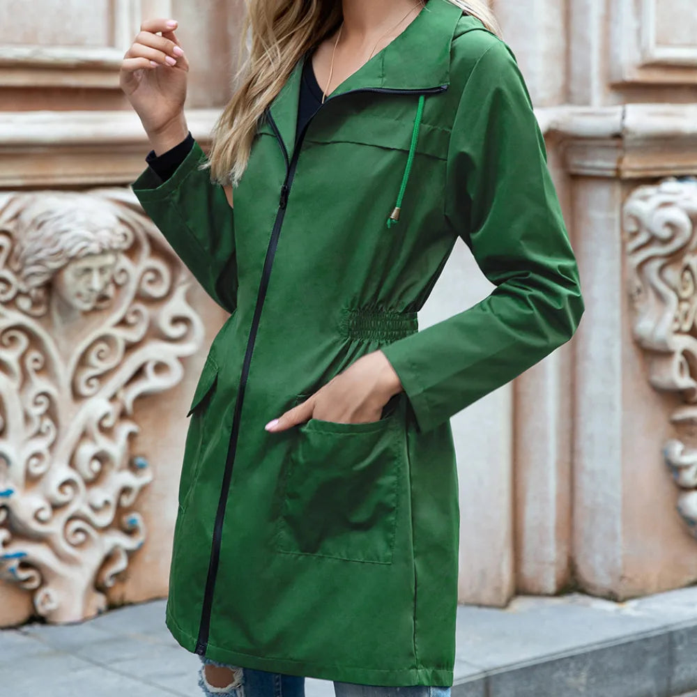 Close-up side view of a green hooded trench coat highlighting the elasticated waist and front patch pocket detail
