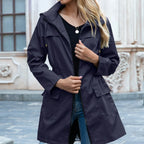 Navy blue hooded zip-up trench coat worn open, showing the drawstring toggles and long sleeve fit