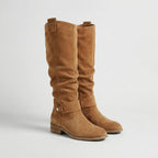 Pair of light brown suede-look knee-high boots with slouchy silhouette, ankle strap and low heel, front angle