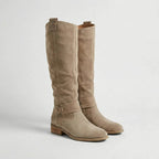 Pair of beige suede-look knee-high boots with relaxed slouch silhouette and low heel, close side view