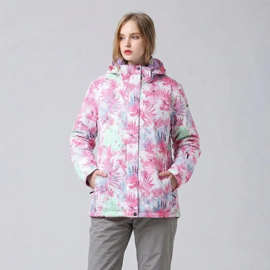 Front view against a grey backdrop of the pink floral print hooded jacket with hands in the zip pockets