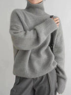 Grey polo neck jumper with ribbed knit texture, worn with a black crossbody bag and grey trousers